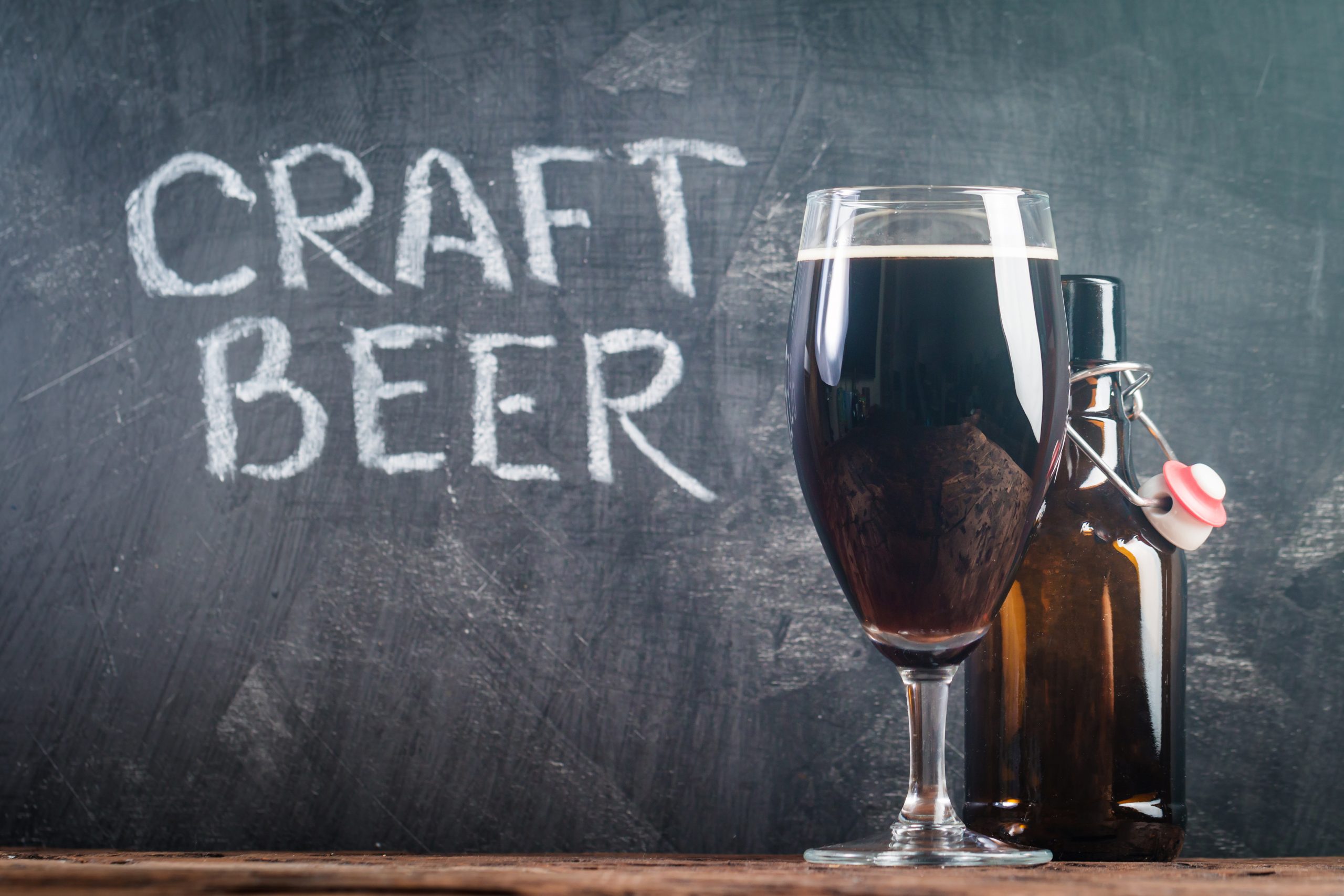 Glass of dark beer with bottle on a chalk board background